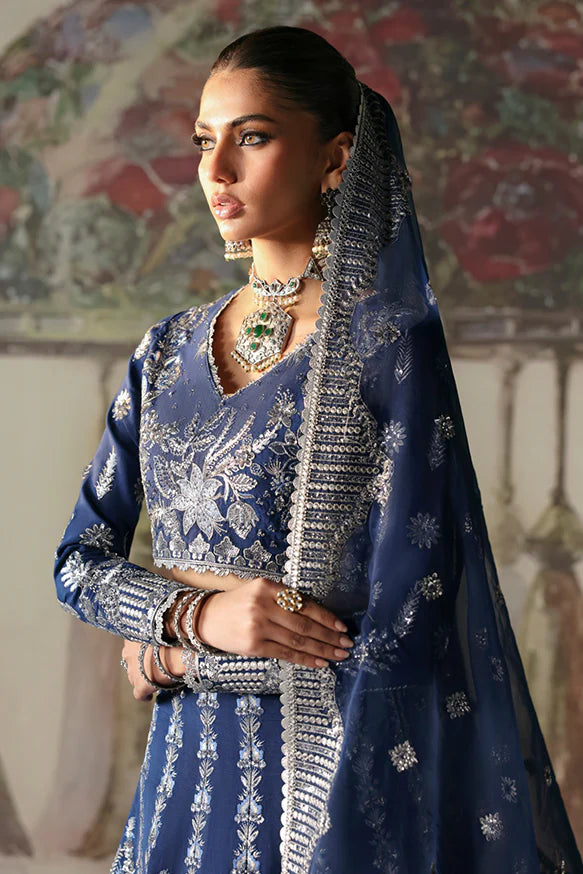 Nazli – Blue embroidered raw silk lehnga choli with sequins, tilla, and silver panni, paired with an embroidered organza dupatta.
